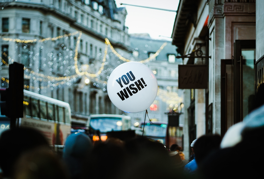 White Balloon with the words YOU WISH! printed in back against a backdrop of a busy street with buses and hanging lights between the high rise buildings