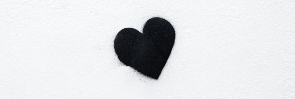 Black love heart shape in the middle of a white background with blurry edges