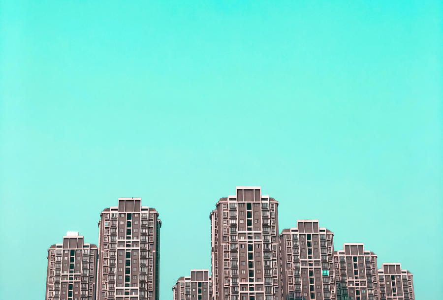 Teal blue colours background with tall business building towers in the foreground at different hights