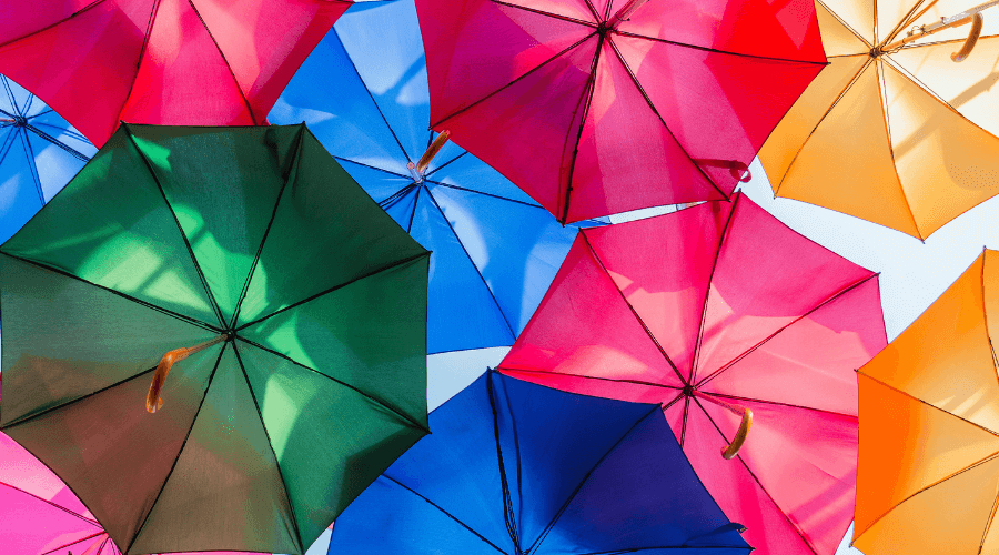 Looking up at a beautiful group of coloured umbrella's open against the bright blue sky with colours beaming from green, pink, yellow to blue