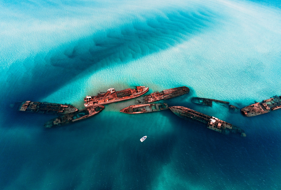 Birds eye view from the sky over the beautiful blue ocean with multiple visible ship wrecks