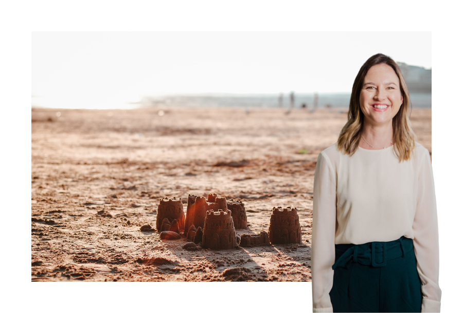 Pictured, Senior Solicitor Gabrielle Andersen standing in front of a beautiful sunset over the beach with deserted sandcastles in the forefront