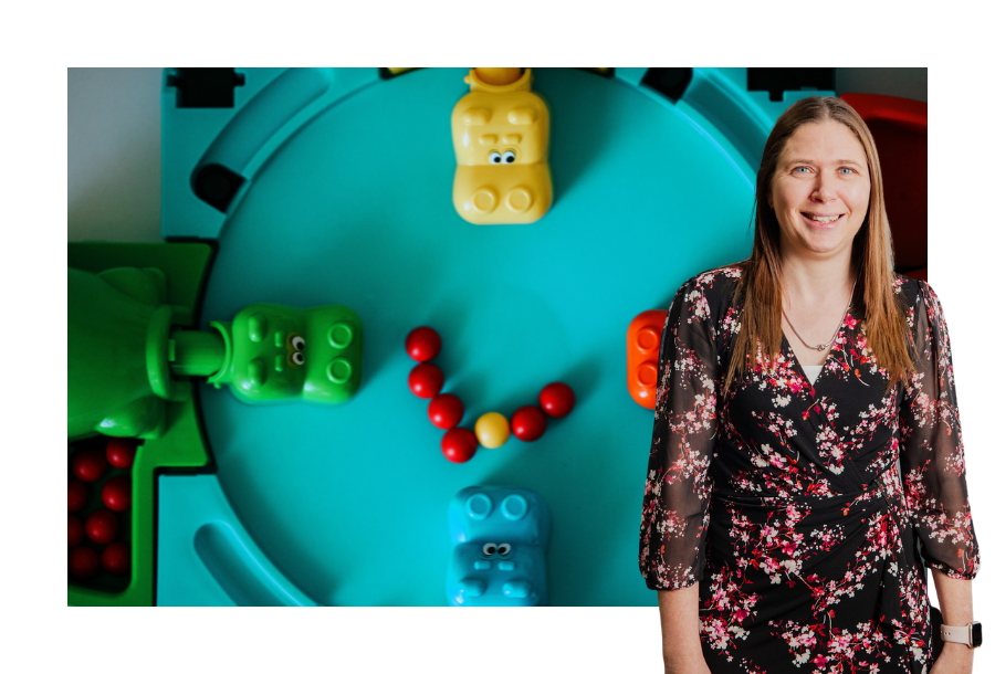 Pictured, Senior Solicitor Karlene Wightman wearing a black and red coloured dress standing against a stock picture of a game of hungry hippos