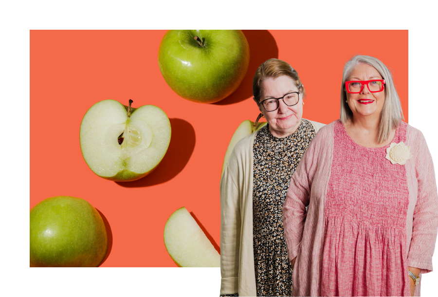 Pictured, NDIS Plan Management team members Christine Friel and Anthea Taylor standing in front of an orange background with green cut open apples.