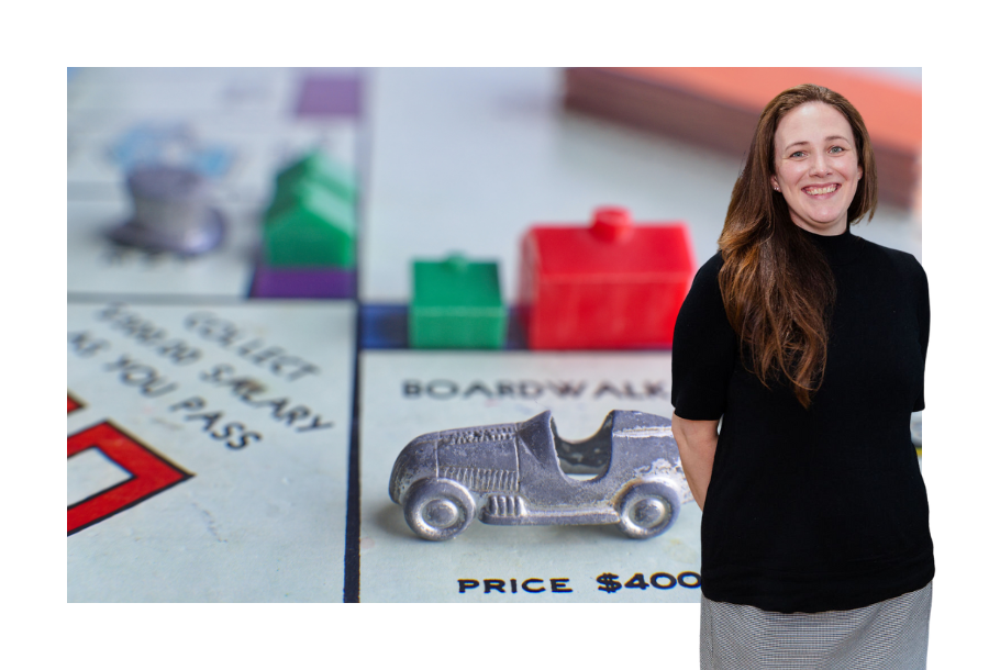 A close up picture of a Monopoly game with a silver car on a square with a small green house and a larger red house, pictured with Jamie Arrington our Accounting Manager.
