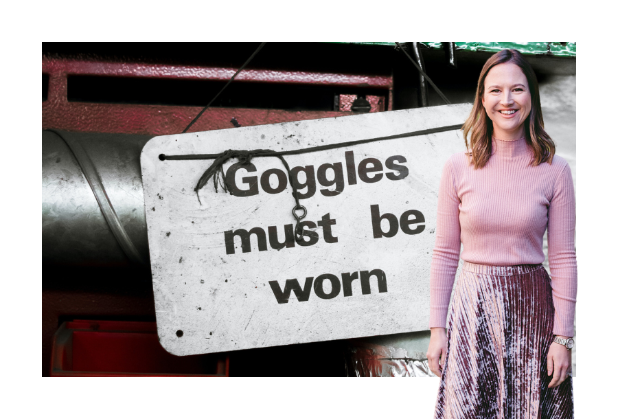 A white, weathered looking sign that says "Goggles must be worn" and standing next to the picture of Director, Gabrielle Andersen