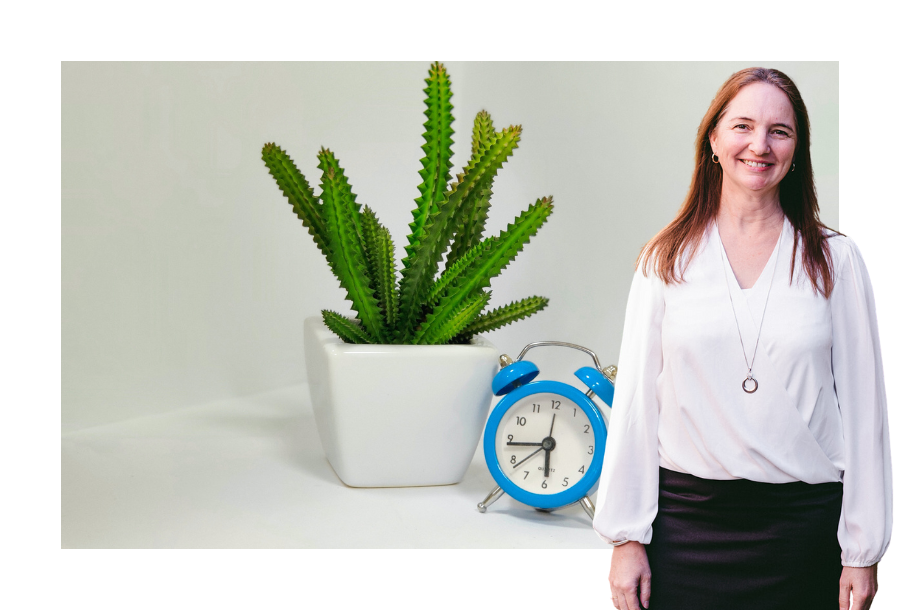 Samantha Butcher wearing a long sleeve white top and a black skirt, standing in front of a stock picture of a blue alarm clock and a potted cactus.