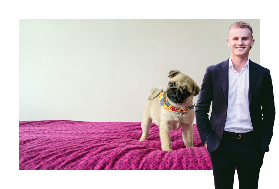 Pictured Jayden Scott, wearing a black soon and his hands in his pockets. Standing in front of a stock picture of a white and black cream coloured pug standing on a bed with a pink doona cover.