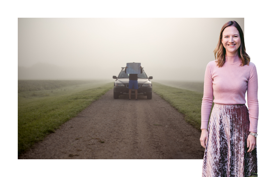 Pictured, Gabrielle Andersen wearing a long sleeve pink skivvy and a velvet purple long skirt and a big smile on her face. In the background is a misty field and a dirty road in the centre, with a man standing in front of his parked car, holding up a map over his face.