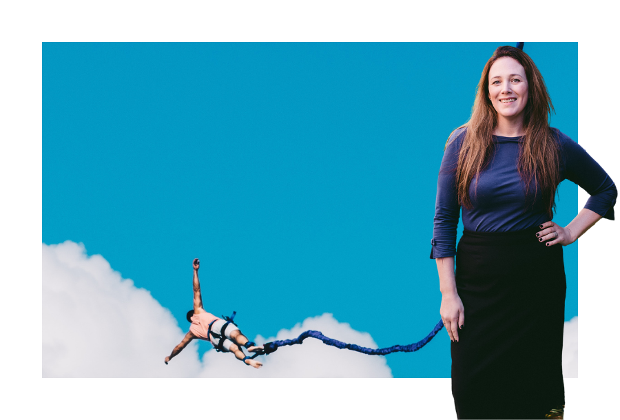 Pictured, Jamie Arrington with one hand on her hip and a big smile on her face. She is wearing a black pencil skirt and a dark blue top and in the background is a picture of the sky and a person bungee jumping!