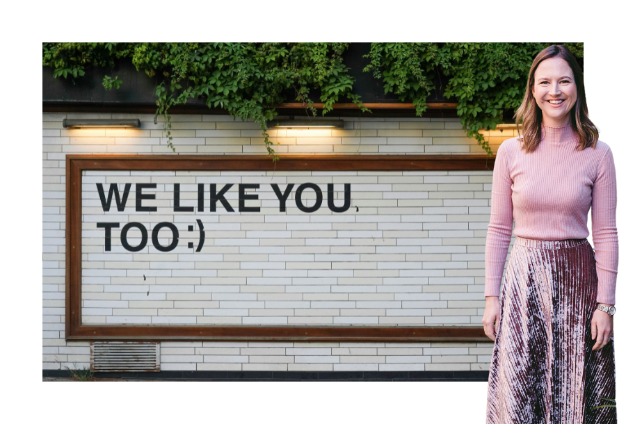 Pictured: Head of Canny Insight, Gabrielle Anderson standing in front of a sign that reads 'We like you too" with a winky face.
