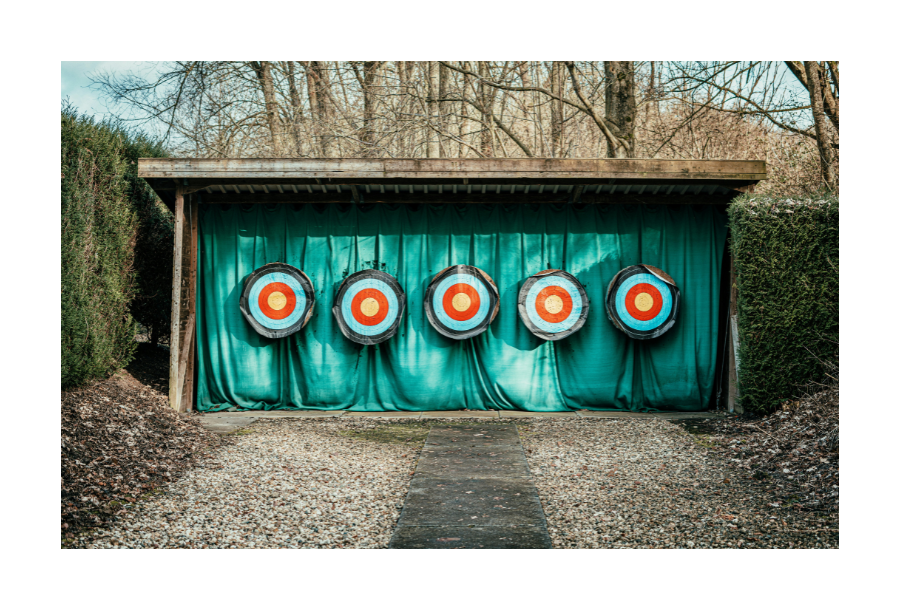 Pictured, a photo of targets setup against a wall with a blue curtain, outside in the woods.