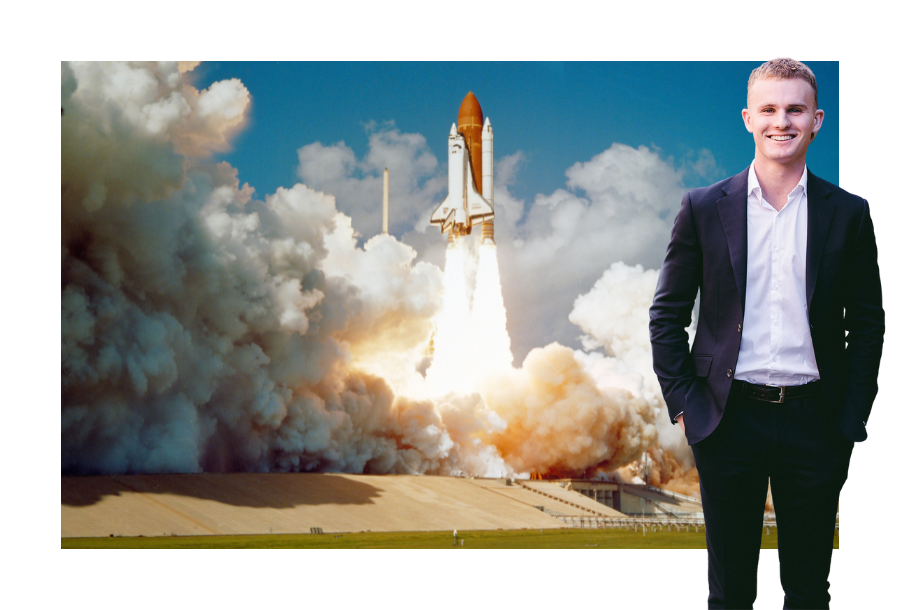 Pictured; Jayden Scott, standing smiling in a dark grey suit. Behind him is a photo of a space shuttle taking off with its thruster creating a large cloud of smoke around it.