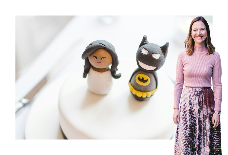 Pictured, Gabrielle Andersen wearing a pink long sleeve top and a pink velvet skirt! In the background is a picture of a white covered wedding style cake, with two Lego figurines sitting on top representing a couple having been married.