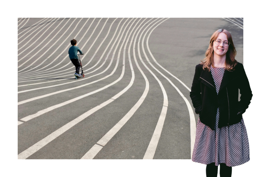 Pictured: Brittany Bell in a pink dress and black jacket with her hands in her jacket pockets, standing and smiling. Behind her is an image of a child on a scooter going down a concrete hill with white stripes painted on the ground.