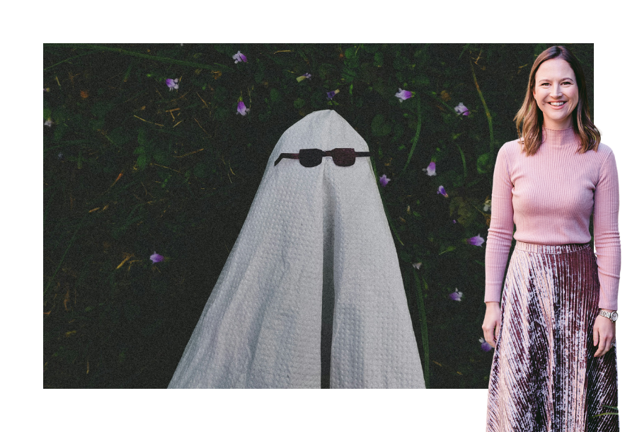 Pictured; Gabrielle Andersen standing smiling in a pink long sleeve shirt and long pink skirt. Behind her is an image of someone wearing a white bed sheet looking like a ghost, with sunglasses over the top of the sheet.