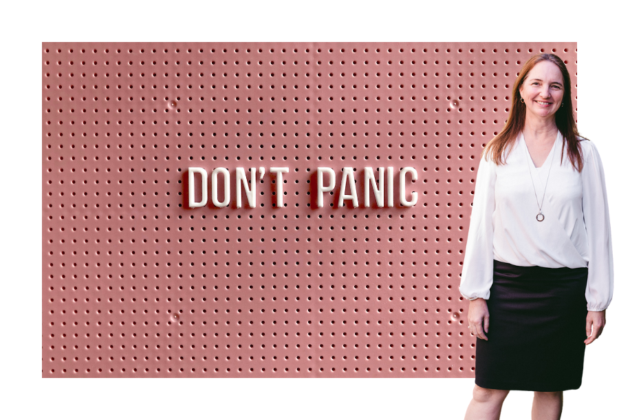 Pictured; Samantha Butcher, standing smiling in a white long sleeve top and a black skirt. Behind her is an image of a pink wall with the words "Don't Panic" on it in a lighter pink colour.