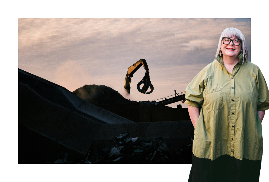 Pictured: Anthea Taylor standing smiling in a green dress, behind her is an image of a scrapy yard and a large construction machine during a sunset.